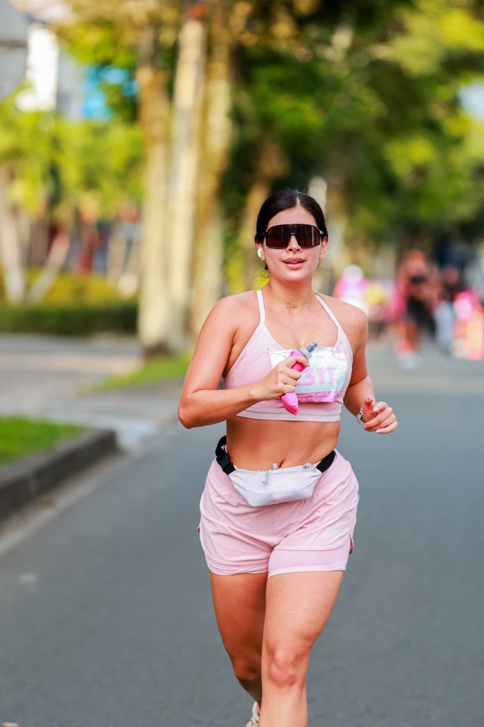 Energetic woman jogging on a sunny day in vibrant pink activewear, showcasing fitness and lifestyle.